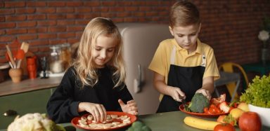 two healthy kids cutting vegetables