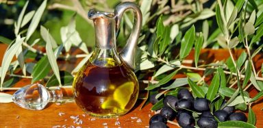 a bottle of olive oil beside an olive tree: an example of healthy fats