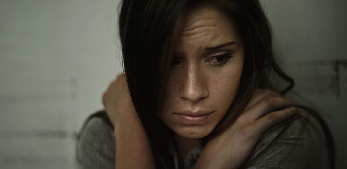 A girl looking sad and holding herself.