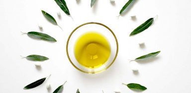 A bowl of olive oil on a white background.