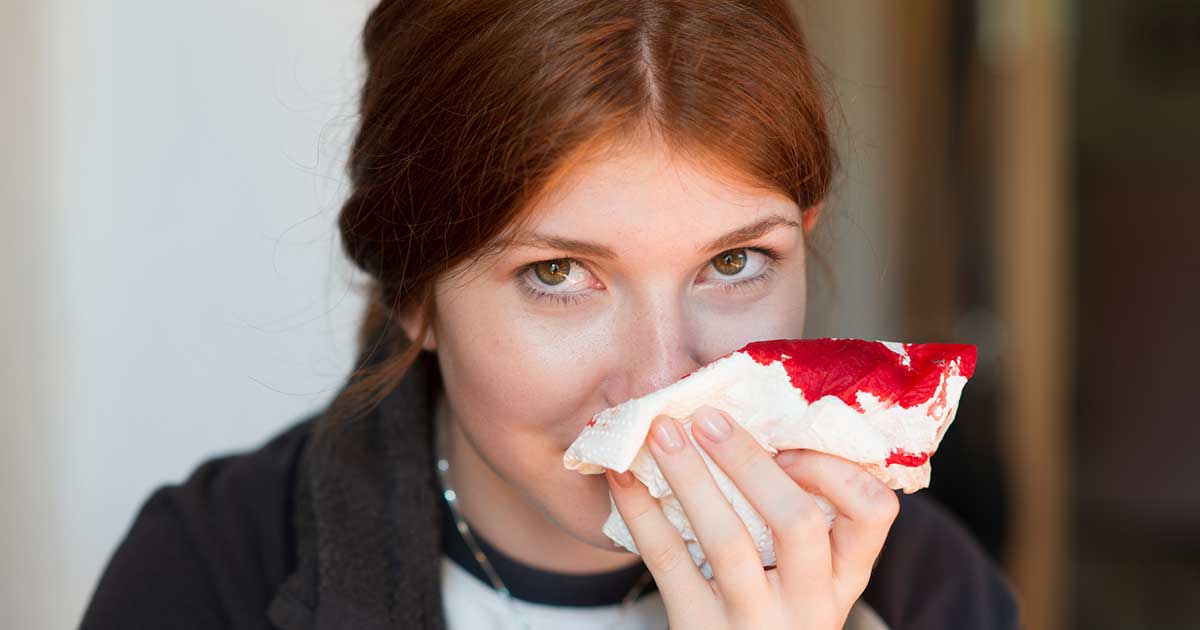 a girl using a tissue to stop a nosebleed