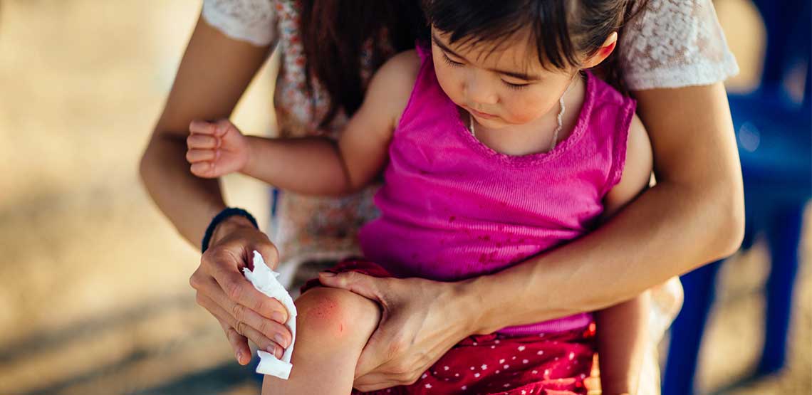 a mother cleaning a wound (minor knee scrape) for her child