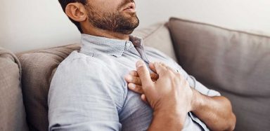 a man holding his chest, experiencing discomfort from heartburn
