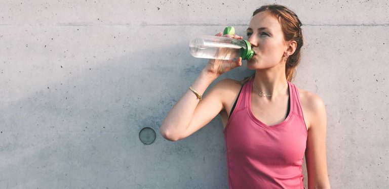 an active woman drinking water to prevent dehydration