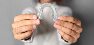hands holding a clear teeth aligner
