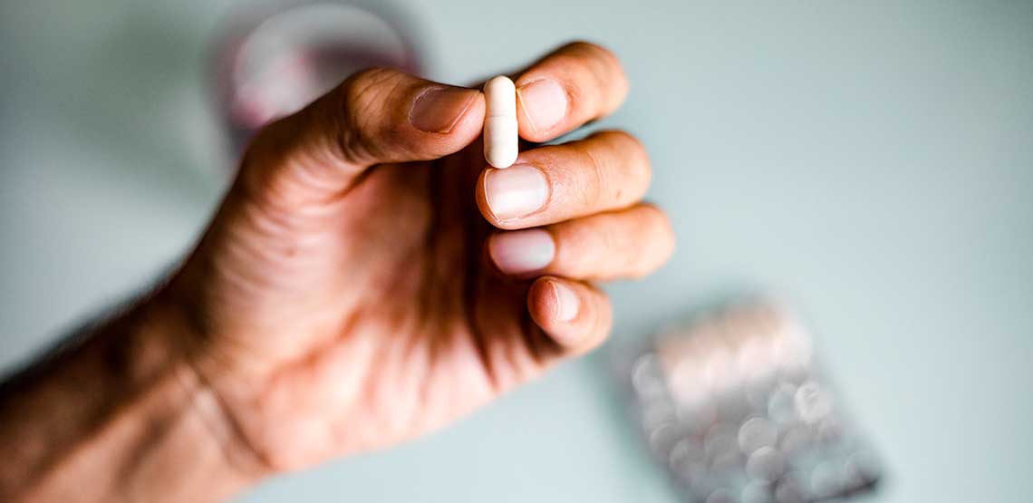 A man holding a pill in his hand.