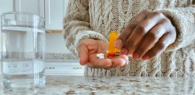 A person putting pills in their hand.