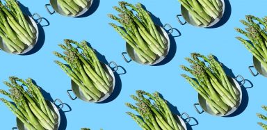 A repeating pattern of a colander full of asparagus on a blue background