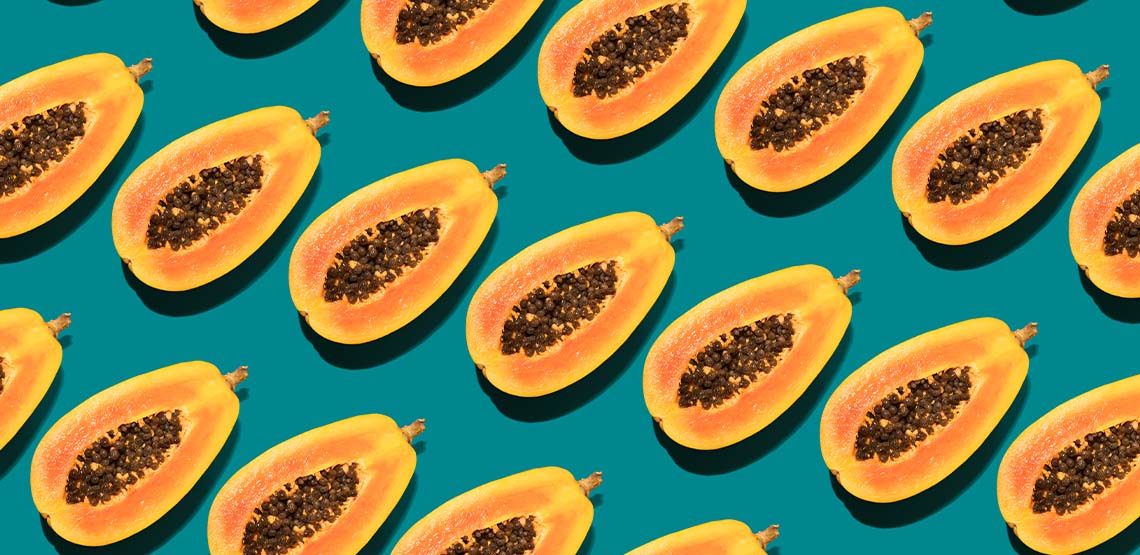 Rows of halved papayas against a teal background.