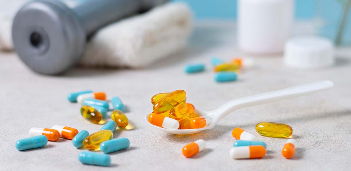 Supplements and vitamins on a white counter in front of a grey weight.