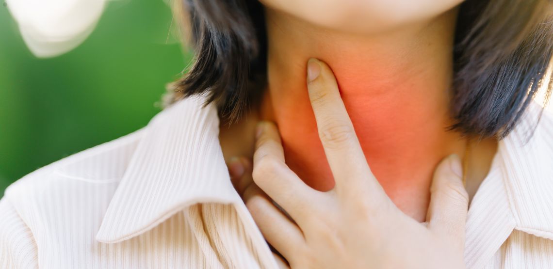 A woman holding her hand to her neck. It has a red color over it to show inflammation and pain.